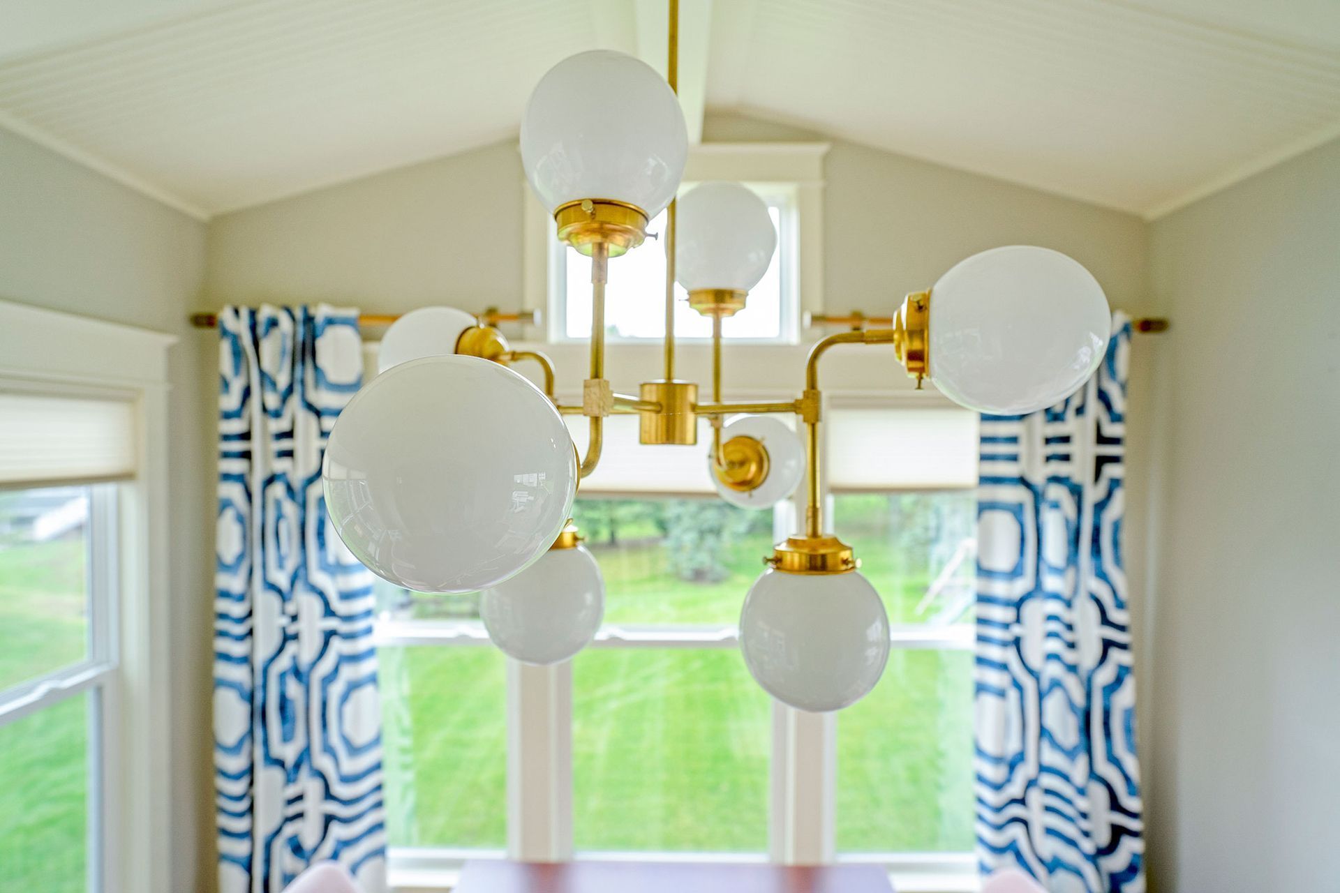A dining room with a chandelier hanging from the ceiling and blue and white curtains