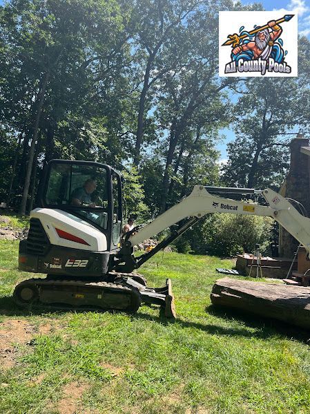 A small excavator is sitting on top of a lush green field.