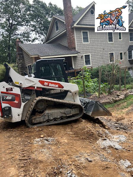 A bulldozer is sitting on a dirt road in front of a house.