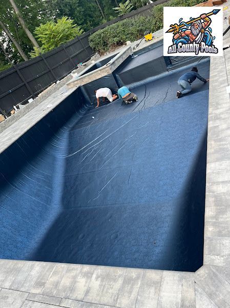 Two men are working on a large swimming pool.