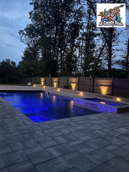 A large swimming pool is lit up at night with blue lights.