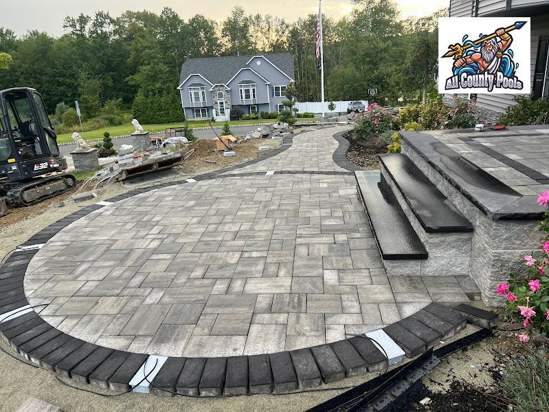 A large brick patio is being built in front of a house.