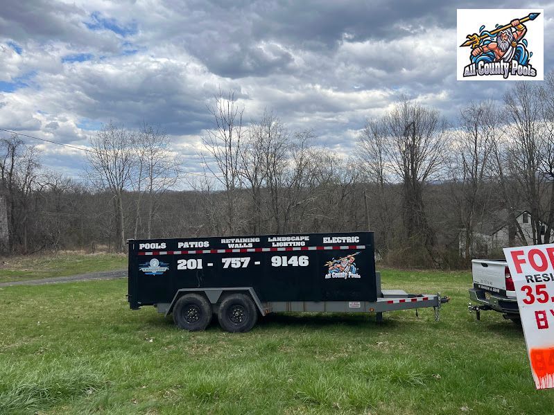 A trailer is parked in a grassy field next to a for sale sign.