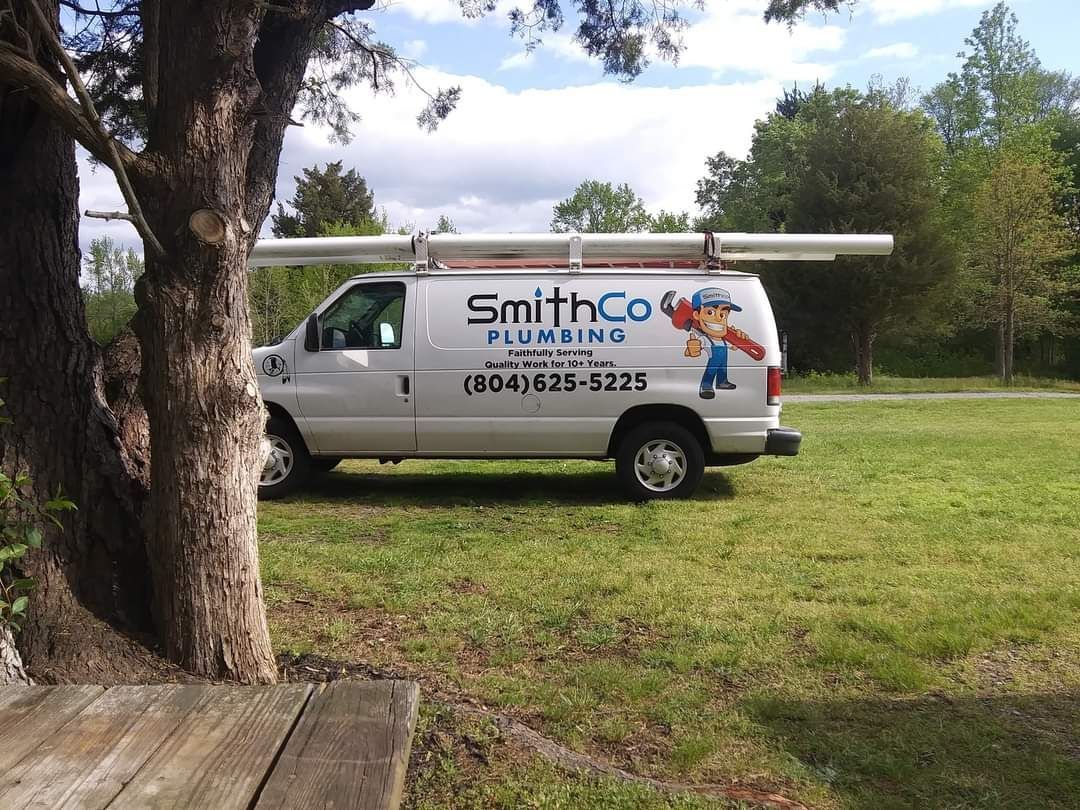 A smith co plumbing van is parked in a grassy field
