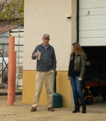 A man and a woman are standing next to each other in front of a garage door