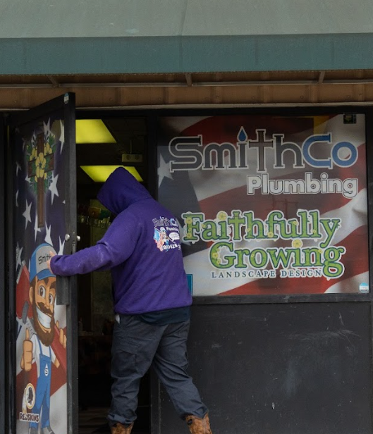 A man in a purple jacket is entering Smith Co Plumbing