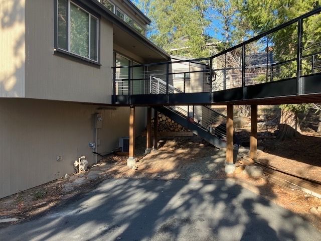Exterior view of a house with a raised deck and a pathway. The deck has black railings and supports.