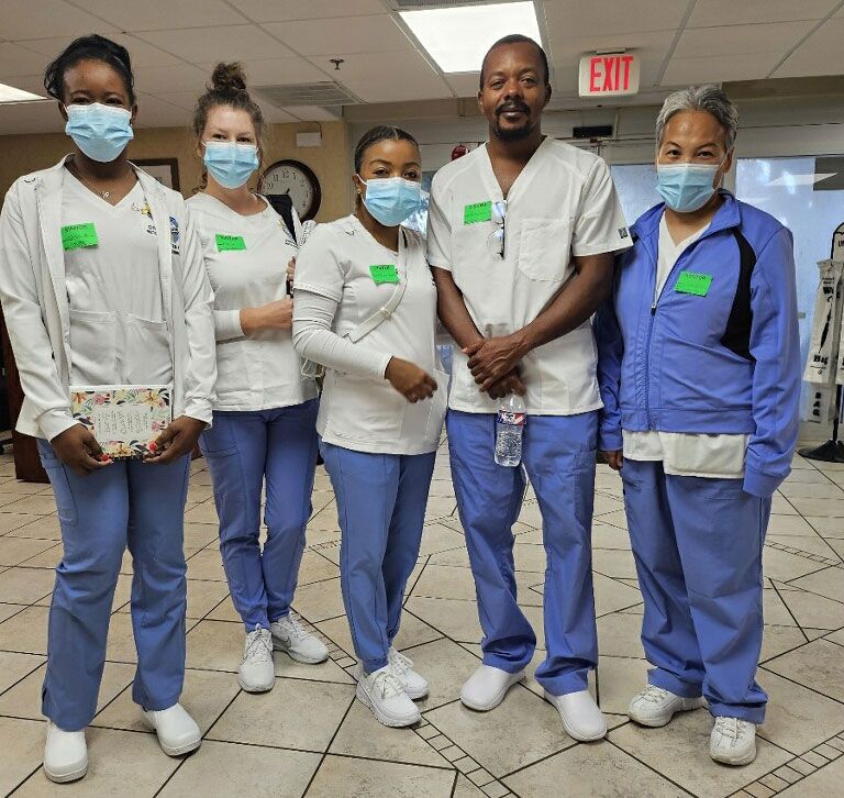 Five healthcare workers wearing masks and scrubs standing in a hallway.