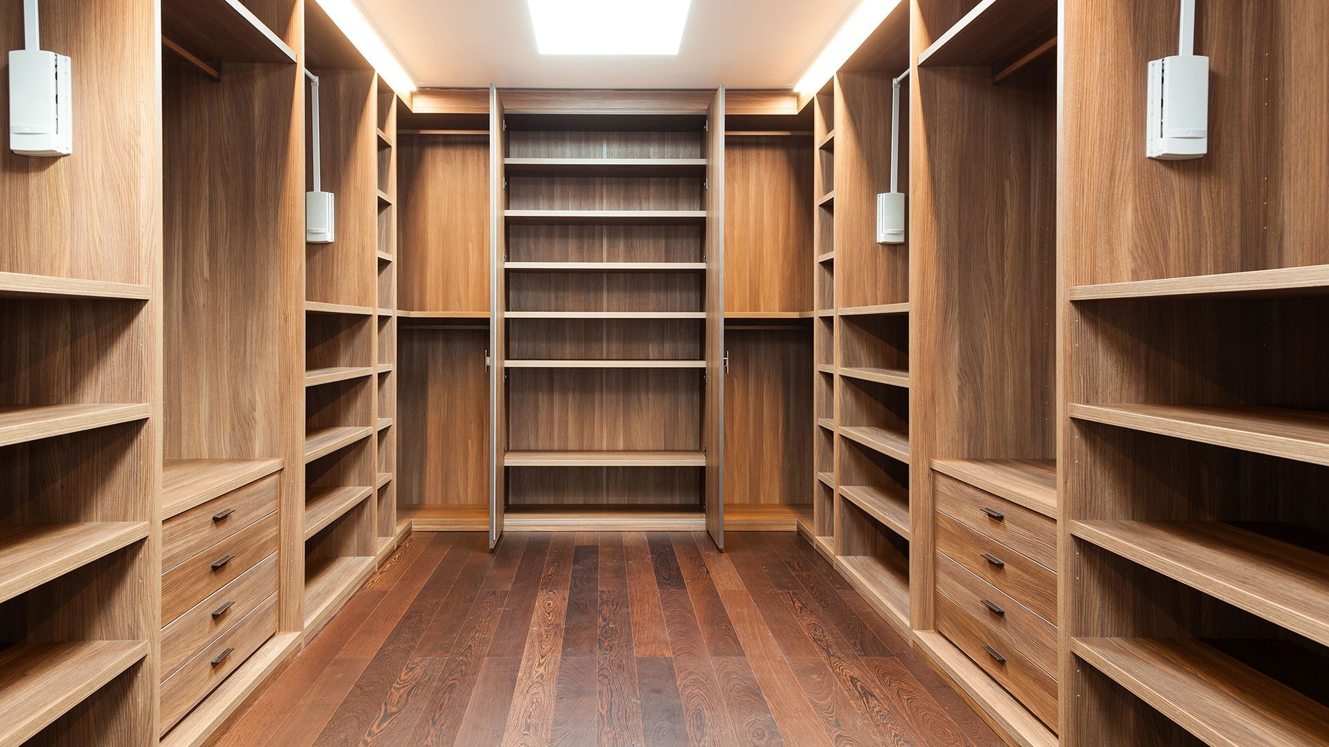 A large walk in closet with wooden shelves and drawers.