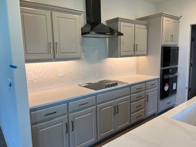 A kitchen with gray cabinets and white counter tops