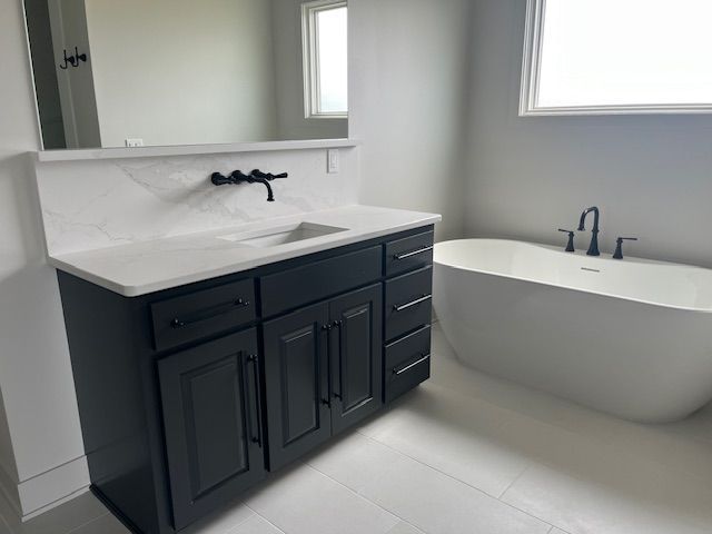 A bathroom with a sink, tub, and mirror.