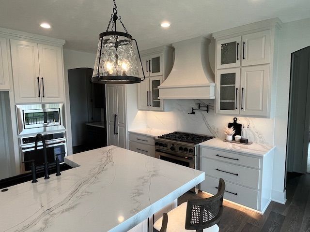 A kitchen with white cabinets, a stove, a sink, and a large island.