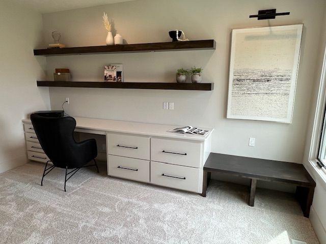 A room with a desk, chair, shelves, and a picture on the wall.