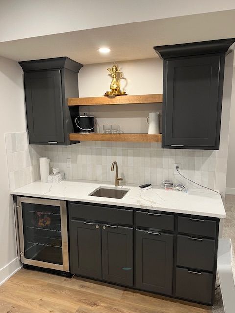 A kitchen with gray cabinets, a sink, and a refrigerator.