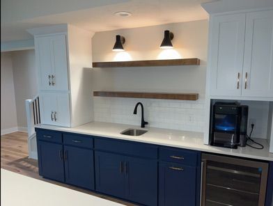 A kitchen with blue cabinets, white cabinets, a sink and a refrigerator.