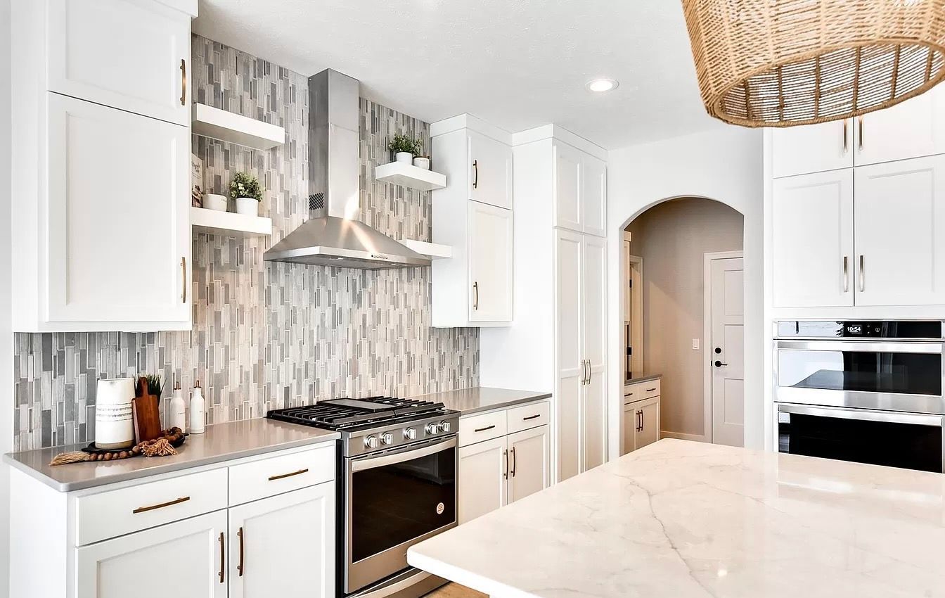 A kitchen with white cabinets , stainless steel appliances , and a large island.