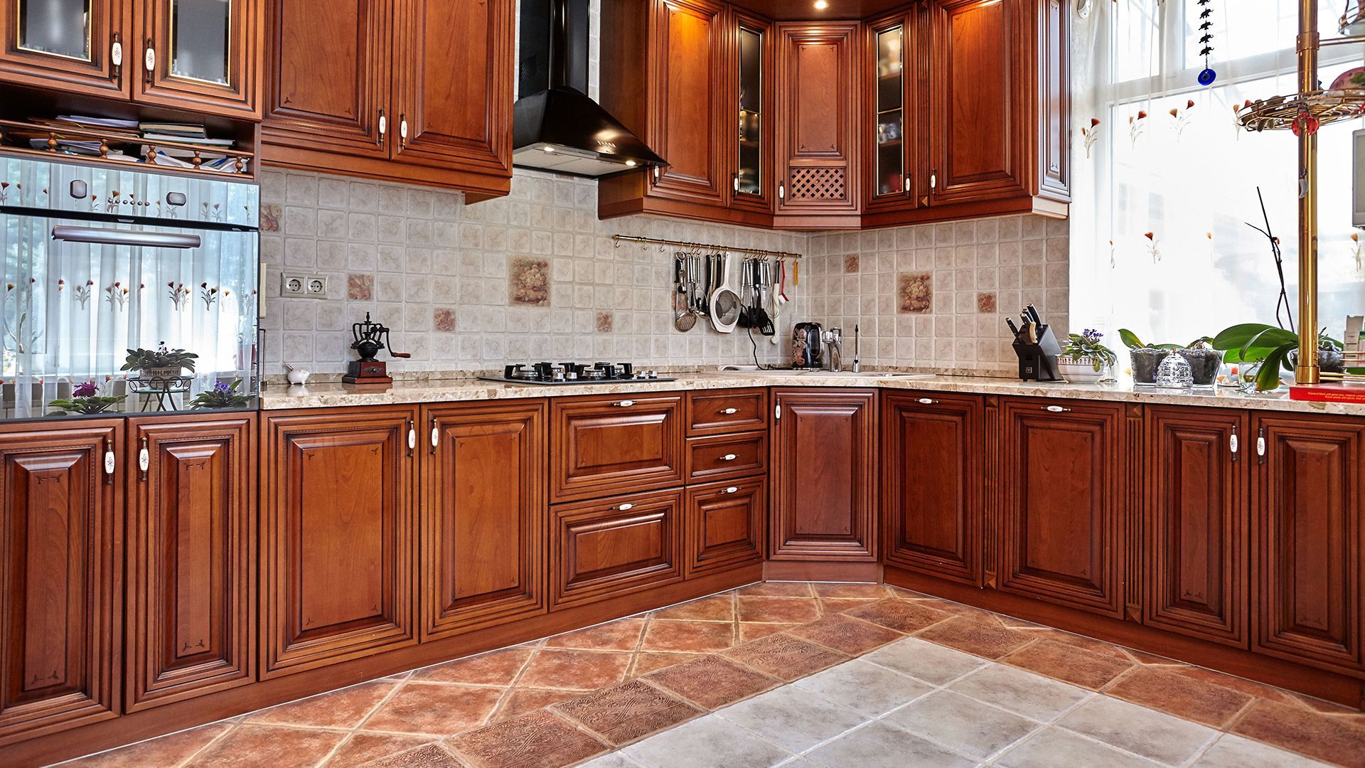 A kitchen with wooden cabinets and a tiled floor