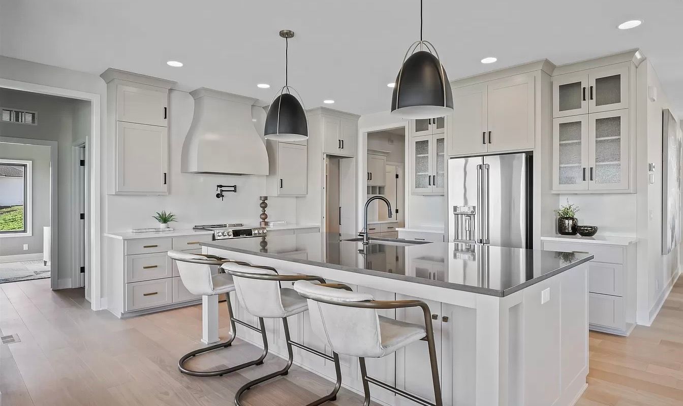 A kitchen with white cabinets , granite counter tops , stainless steel appliances and a large island.