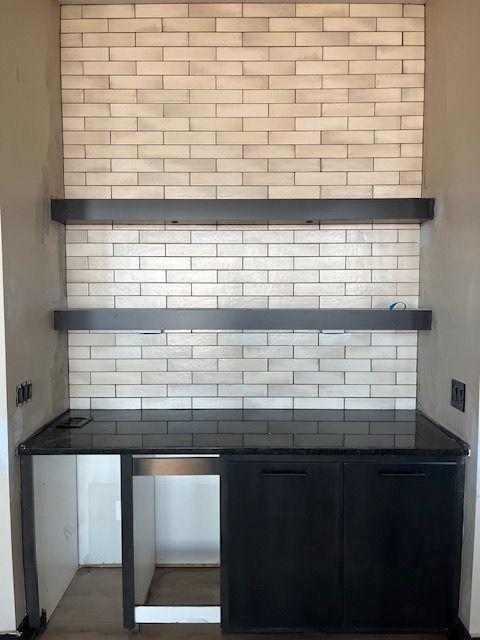 A kitchen with a brick wall and black cabinets