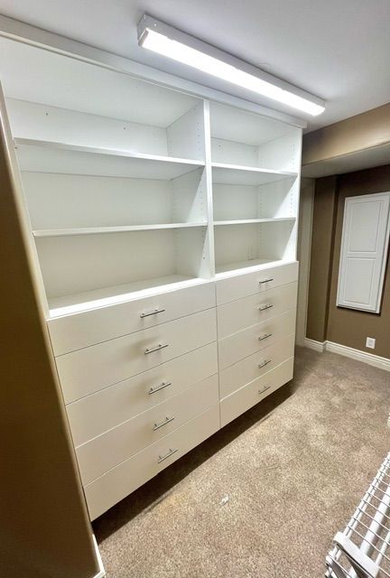 A walk in closet with lots of shelves and drawers.