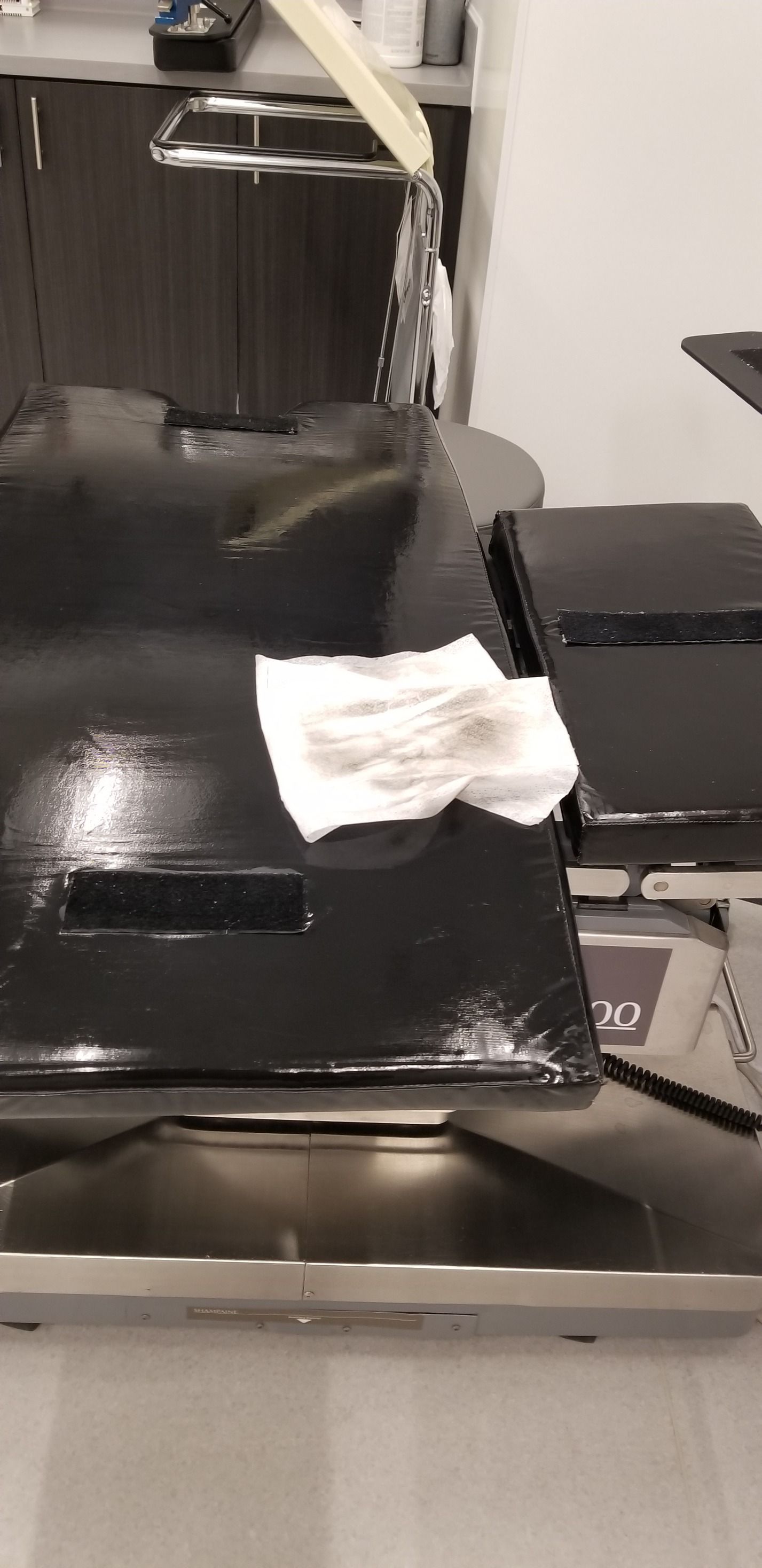A person cleans a black surface with a paper towel. Water is pouring from a spout above.