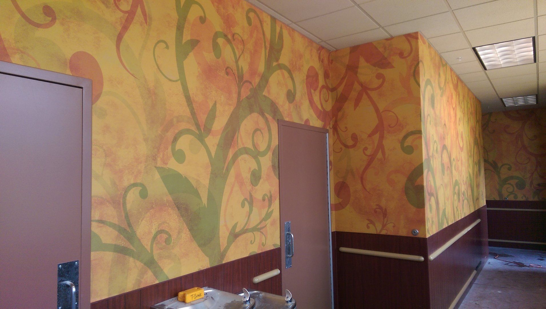 A hallway with a mural on the wall and a sink.