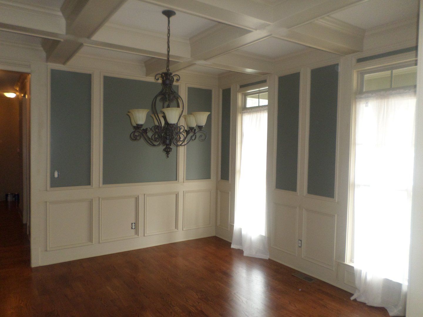 An empty dining room with a chandelier hanging from the ceiling.