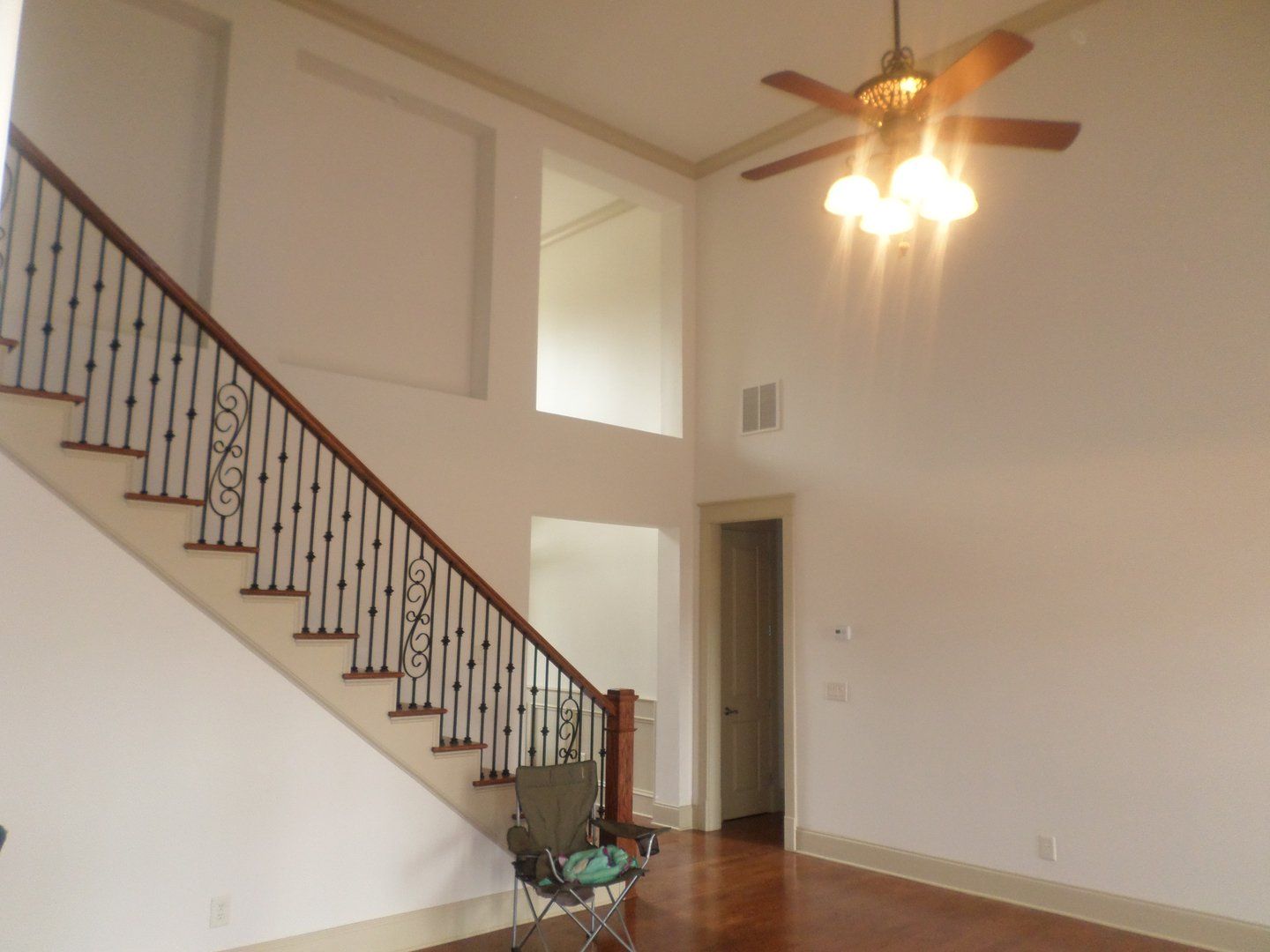 An empty living room with stairs and a ceiling fan