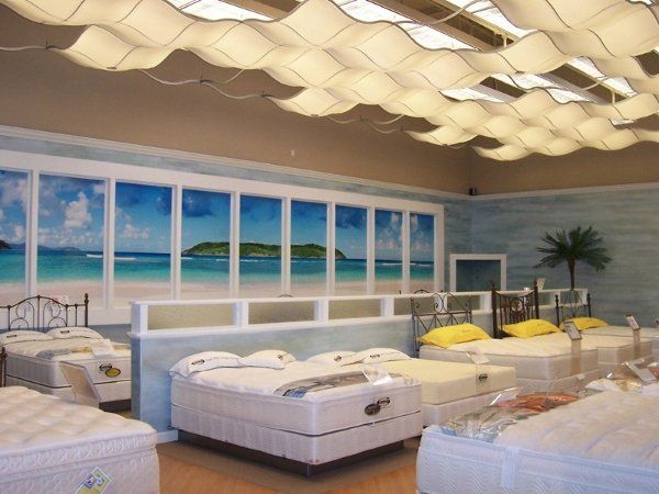 A room with a lot of beds and a picture of a beach on the wall