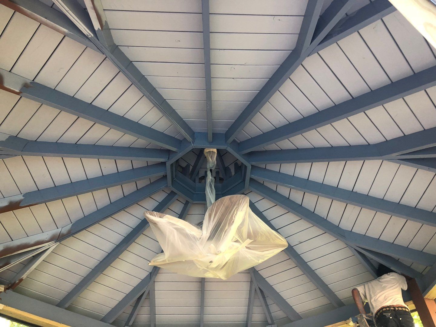A man is painting the ceiling of a gazebo