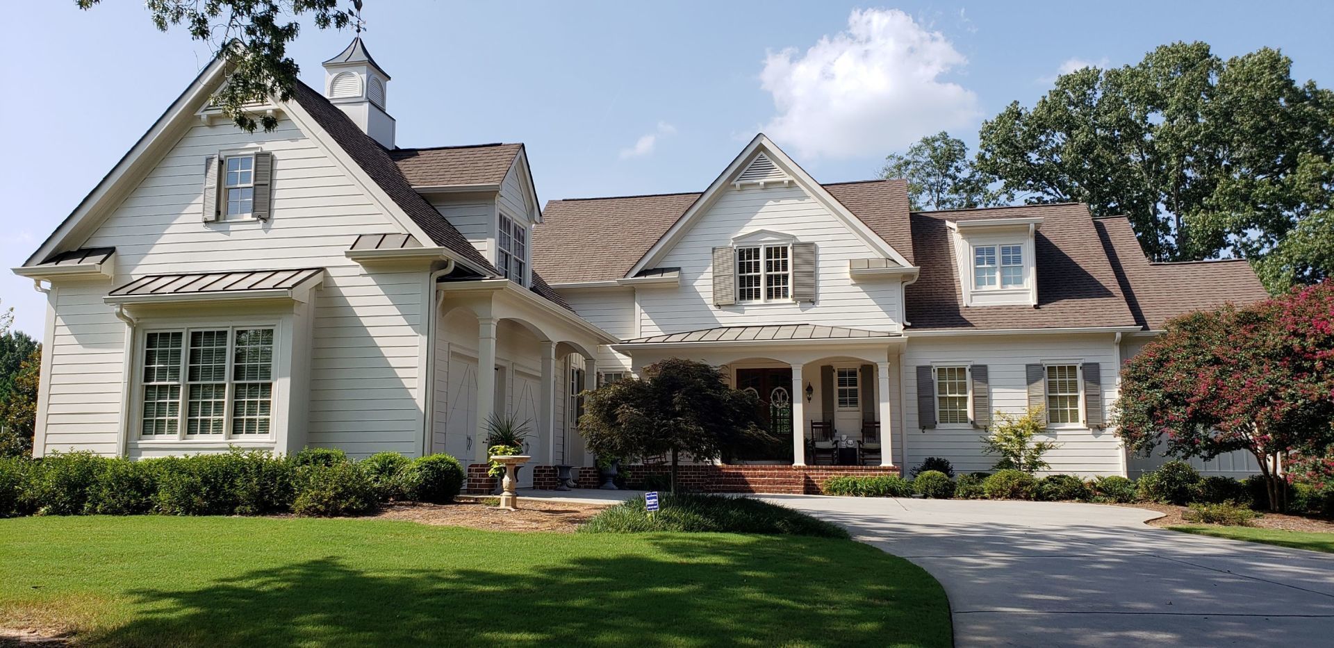 A large white house with a brown roof and a driveway