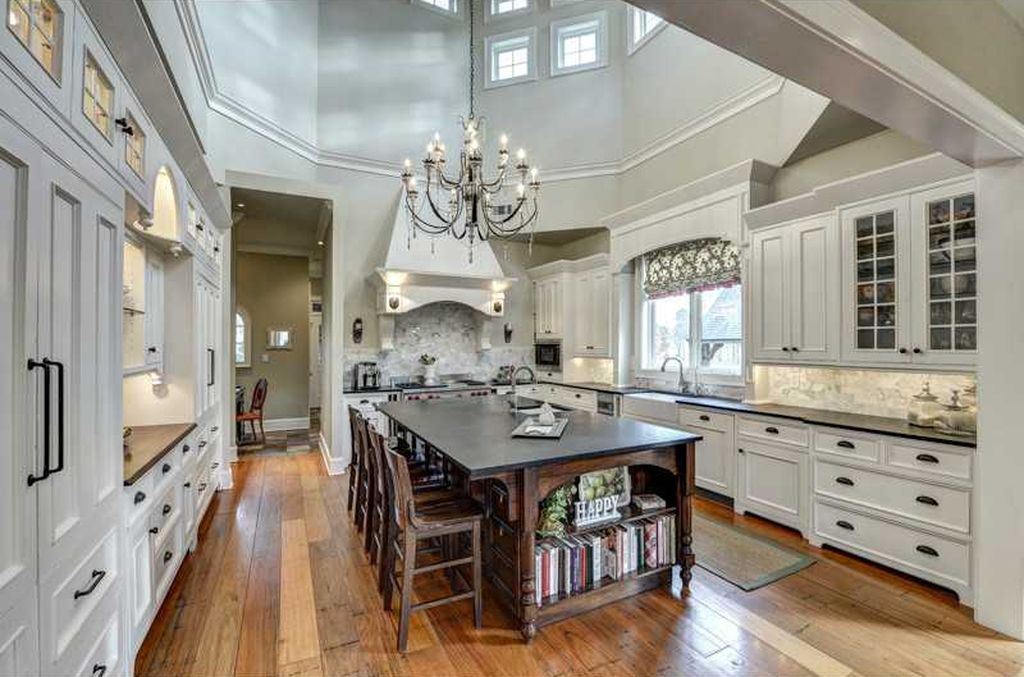A large kitchen with white cabinets and a large island in the middle.
