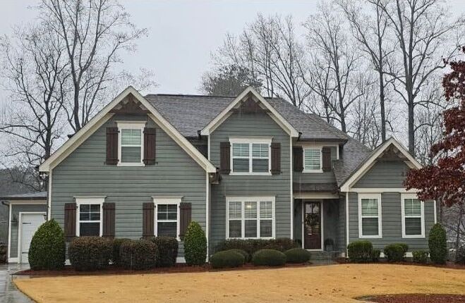 A large house with a lot of windows and shutters on a cloudy day.