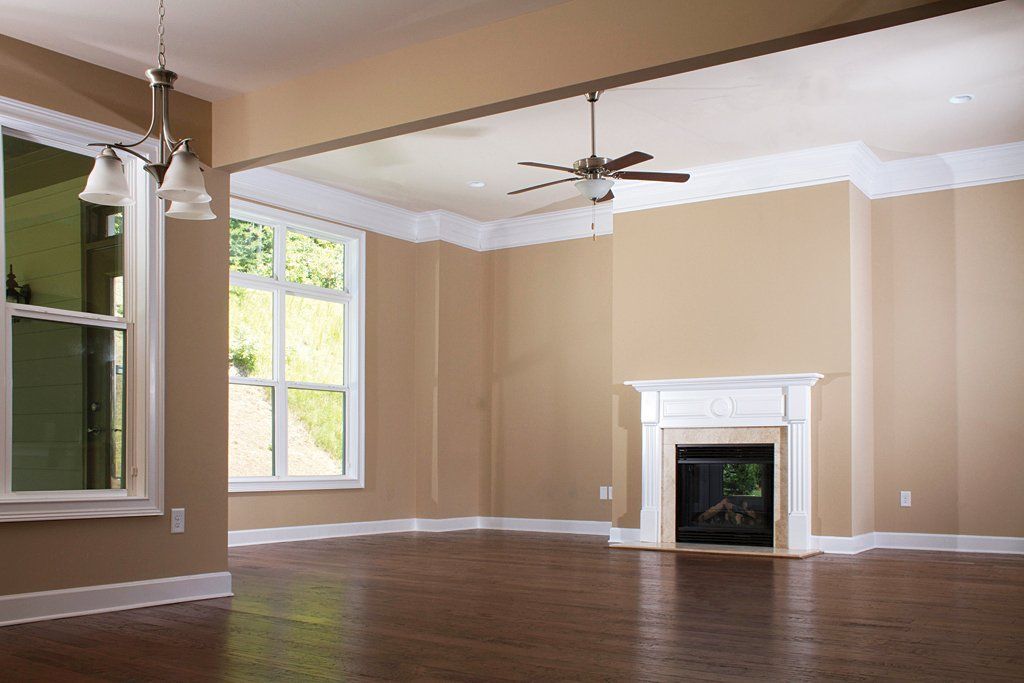 An empty living room with a fireplace and ceiling fan
