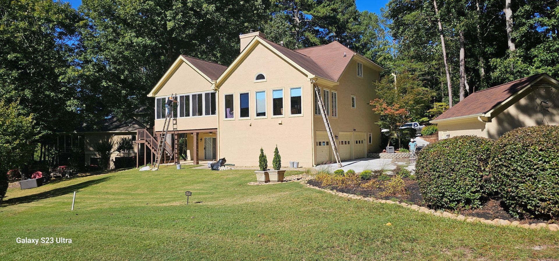 A large house with a lot of windows is sitting on top of a lush green field.