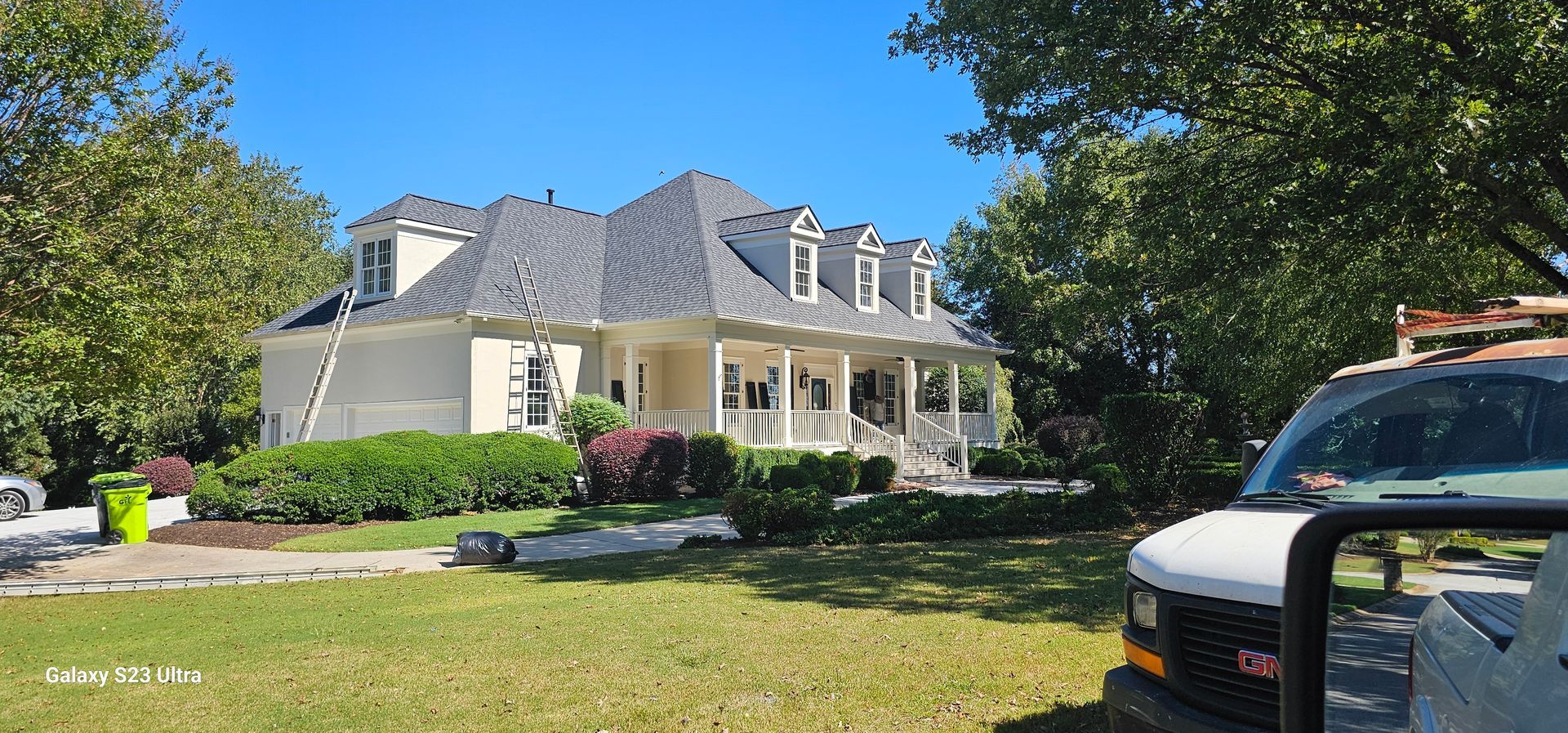 A white van is parked in front of a large white house.