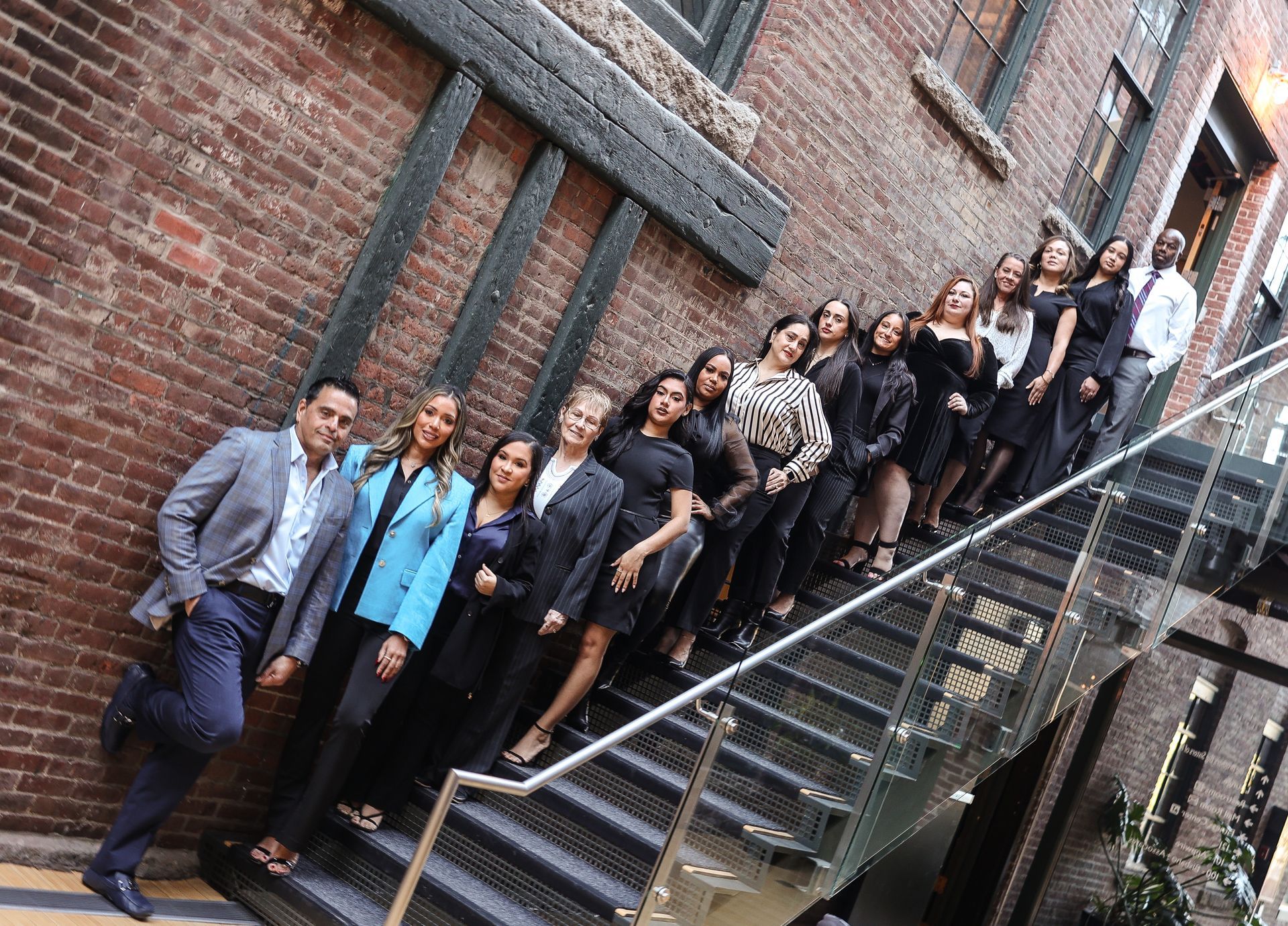 Group of people posing for a photo in an interior courtyard with brick walls.