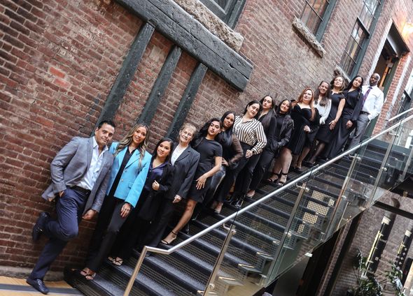 Group of people posing for a photo in an interior courtyard with brick walls.