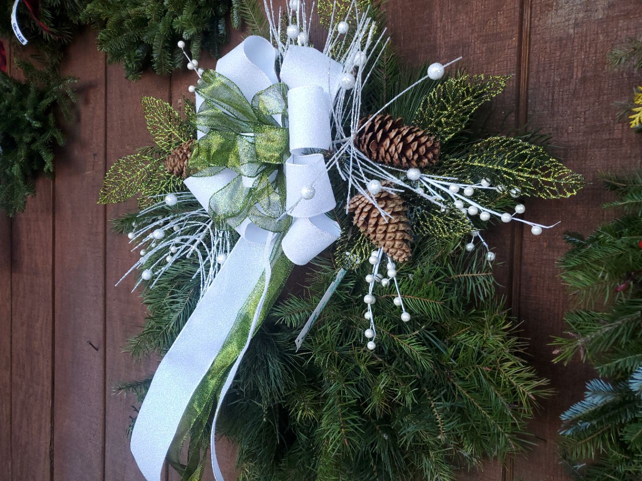A christmas wreath is hanging on a wooden wall.