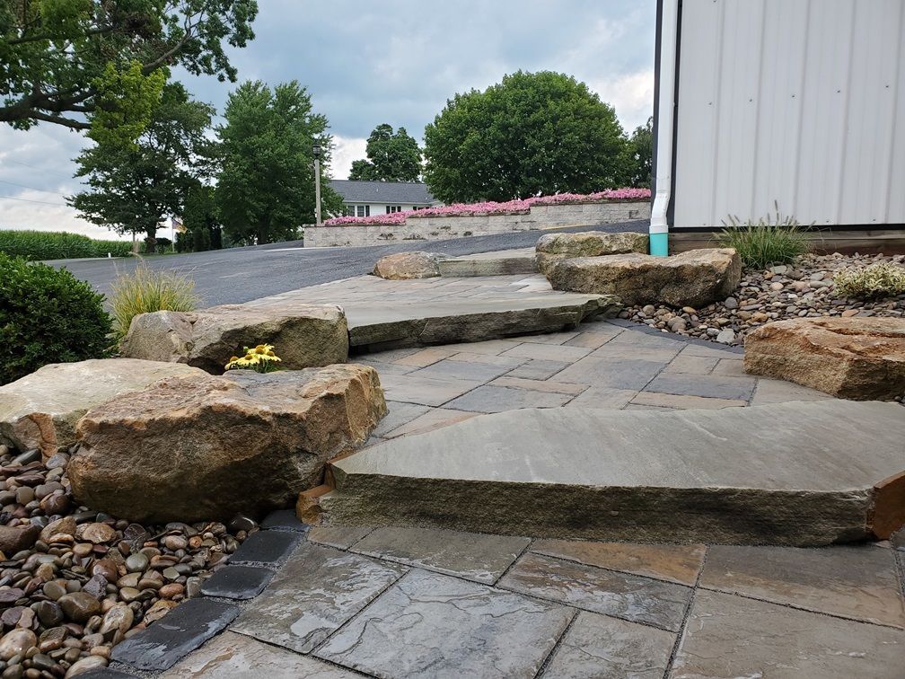 A stone walkway with rocks and steps leading to a house.