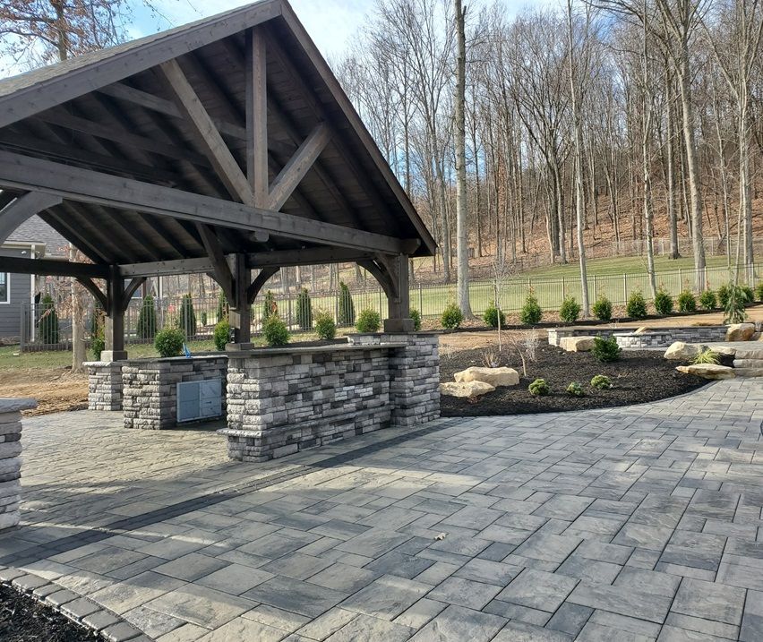 A patio with a wooden gazebo and a stone counter top.