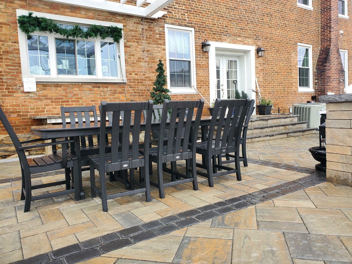 A patio with a table and chairs in front of a brick house.