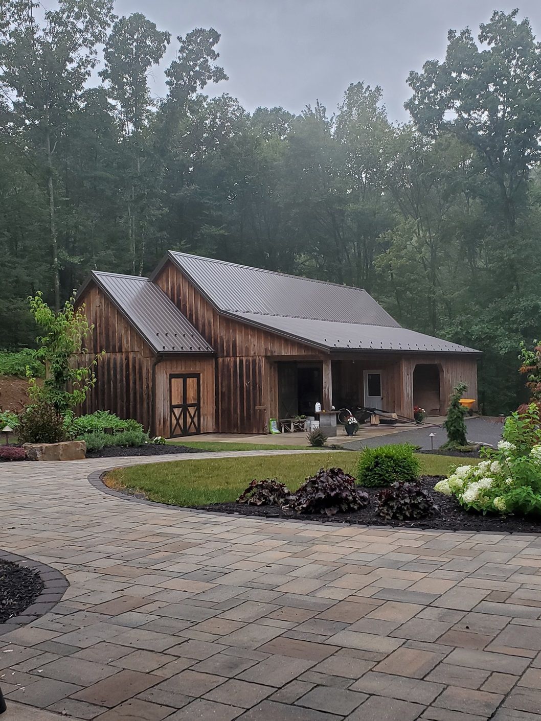 A wooden house with a brick driveway in front of it