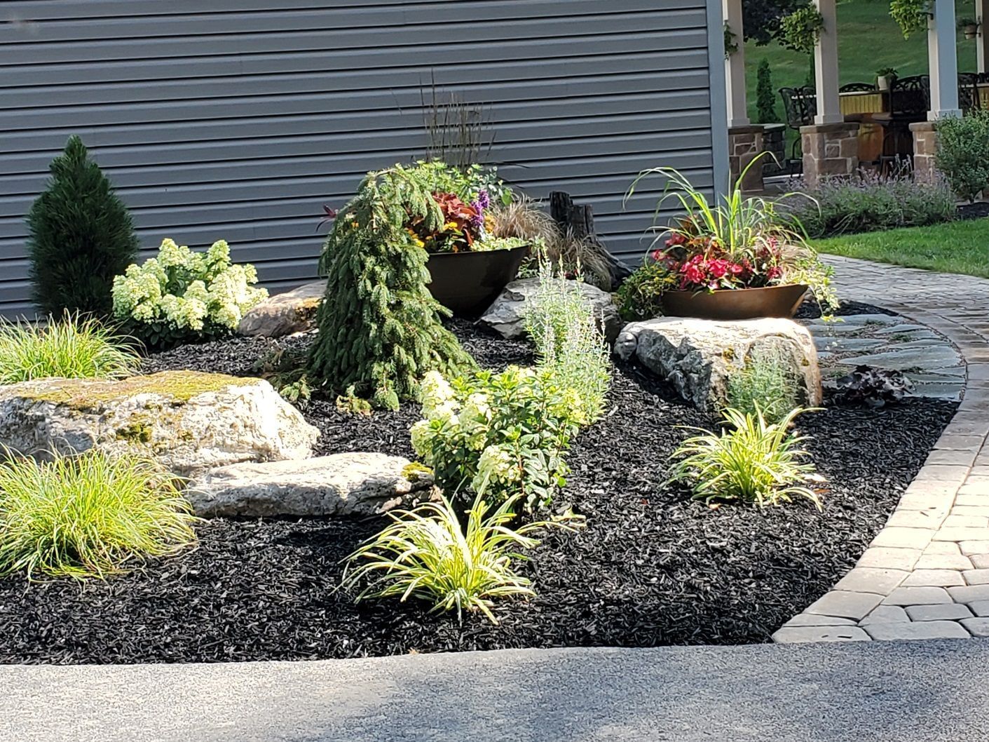 A garden with rocks and plants in front of a house.