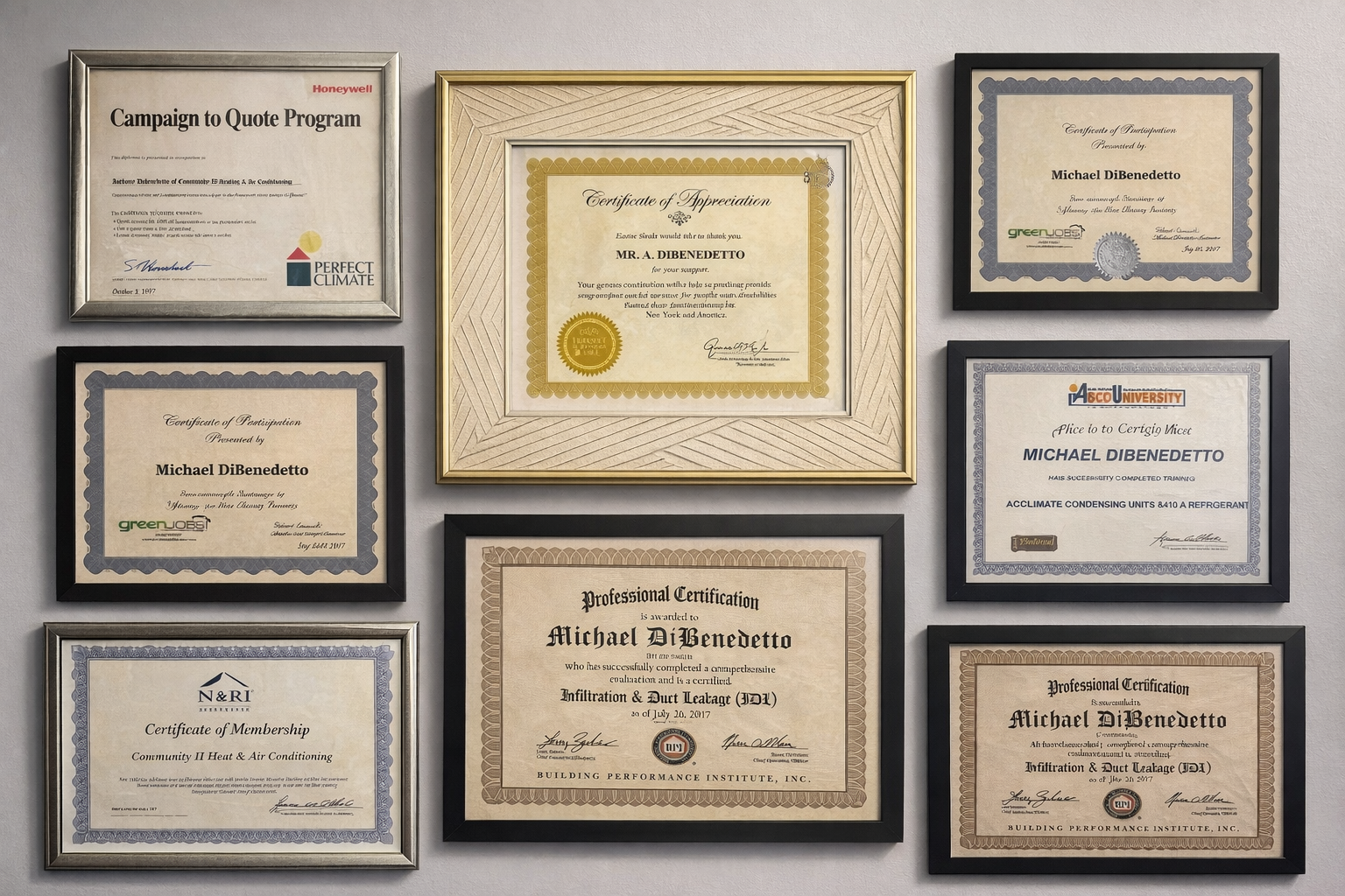 A wall display of eight framed awards and professional certificates arranged in a grid pattern.