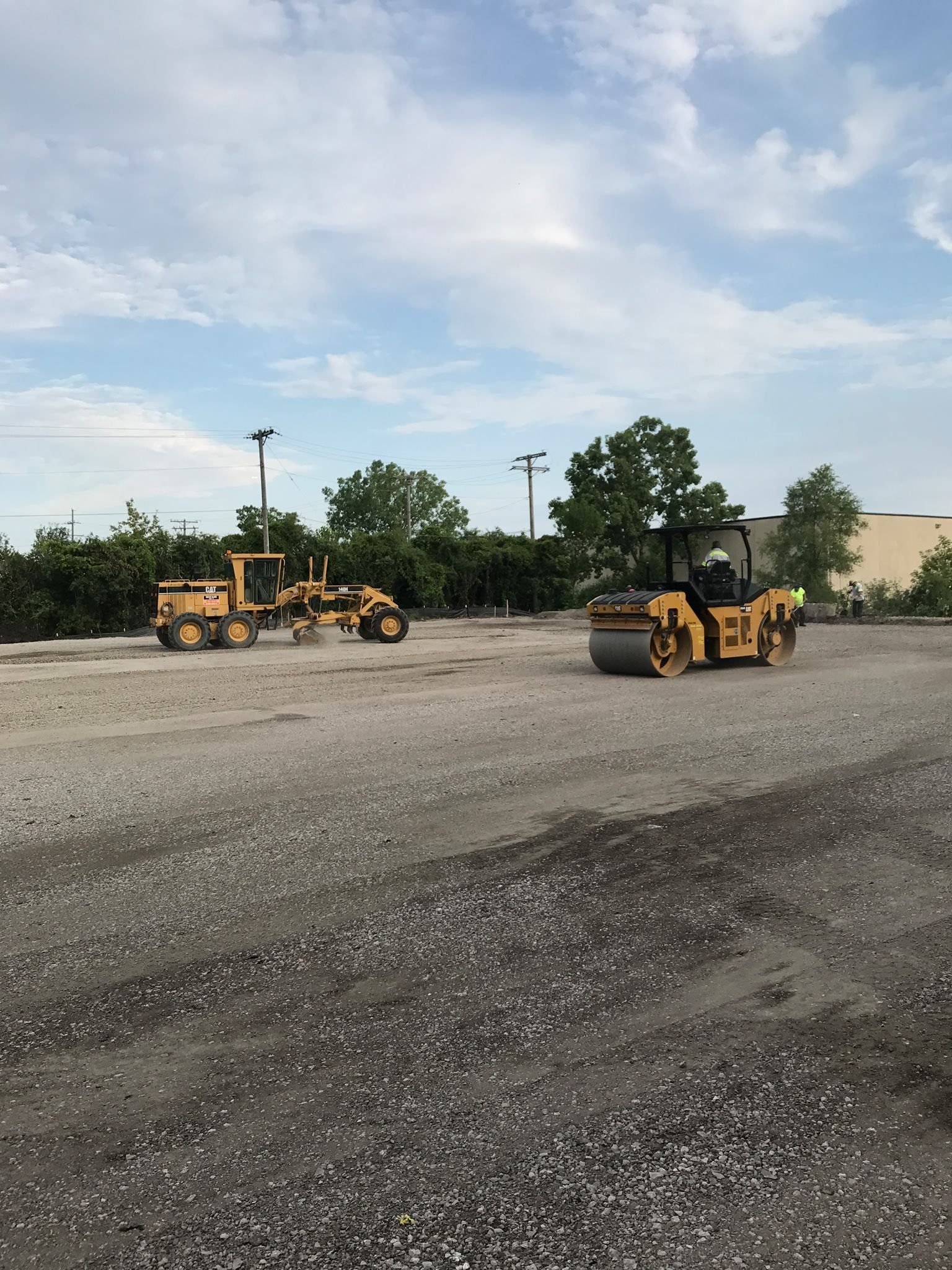 A couple of yellow tractors are driving down a dirt road.