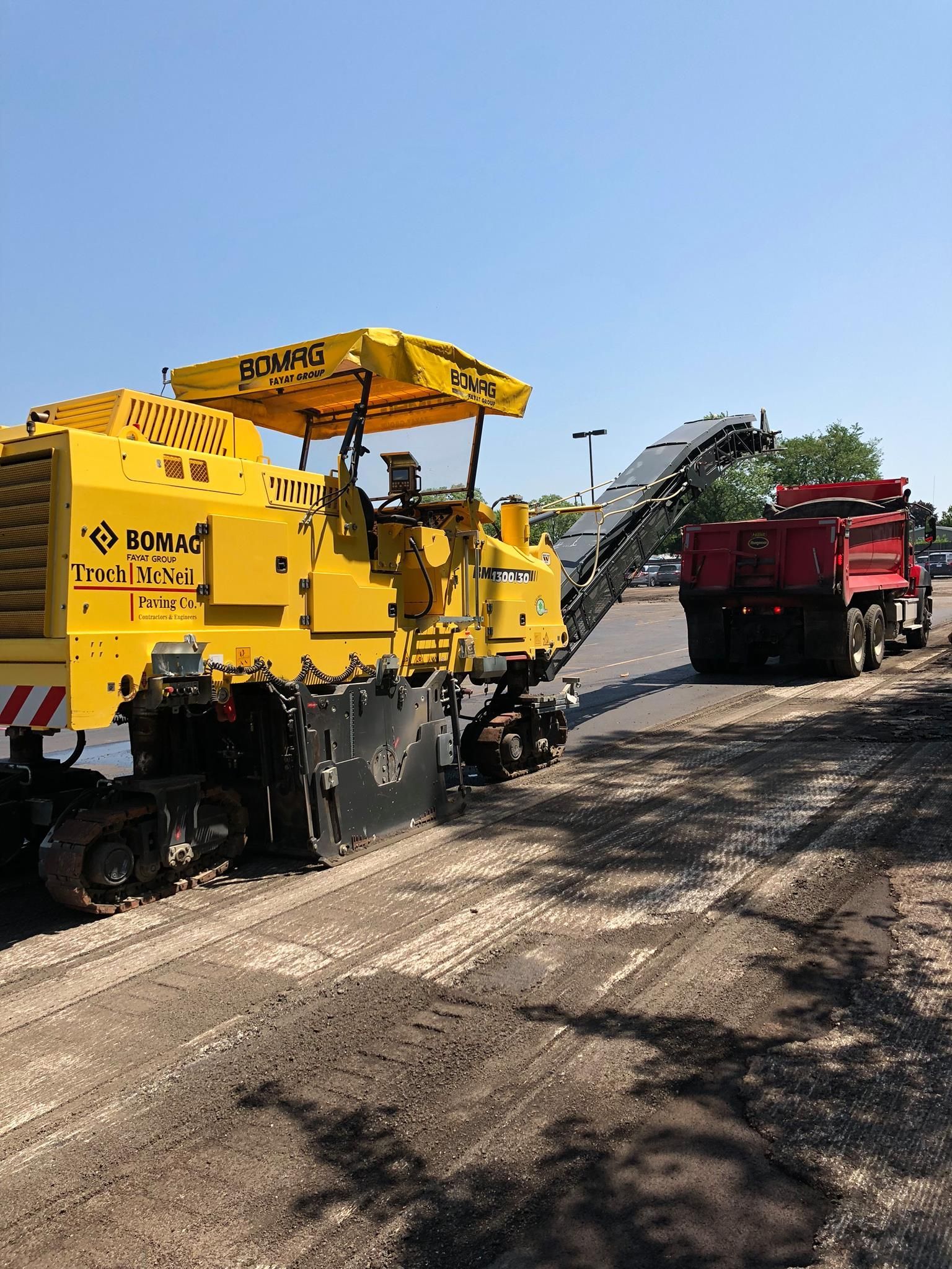 A yellow machine is cutting asphalt on a road.