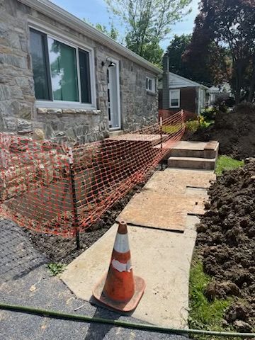 A concrete walkway is being built in front of a stone house.