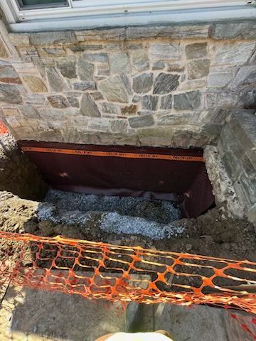 A person is standing in front of a stone wall with a hole in it.