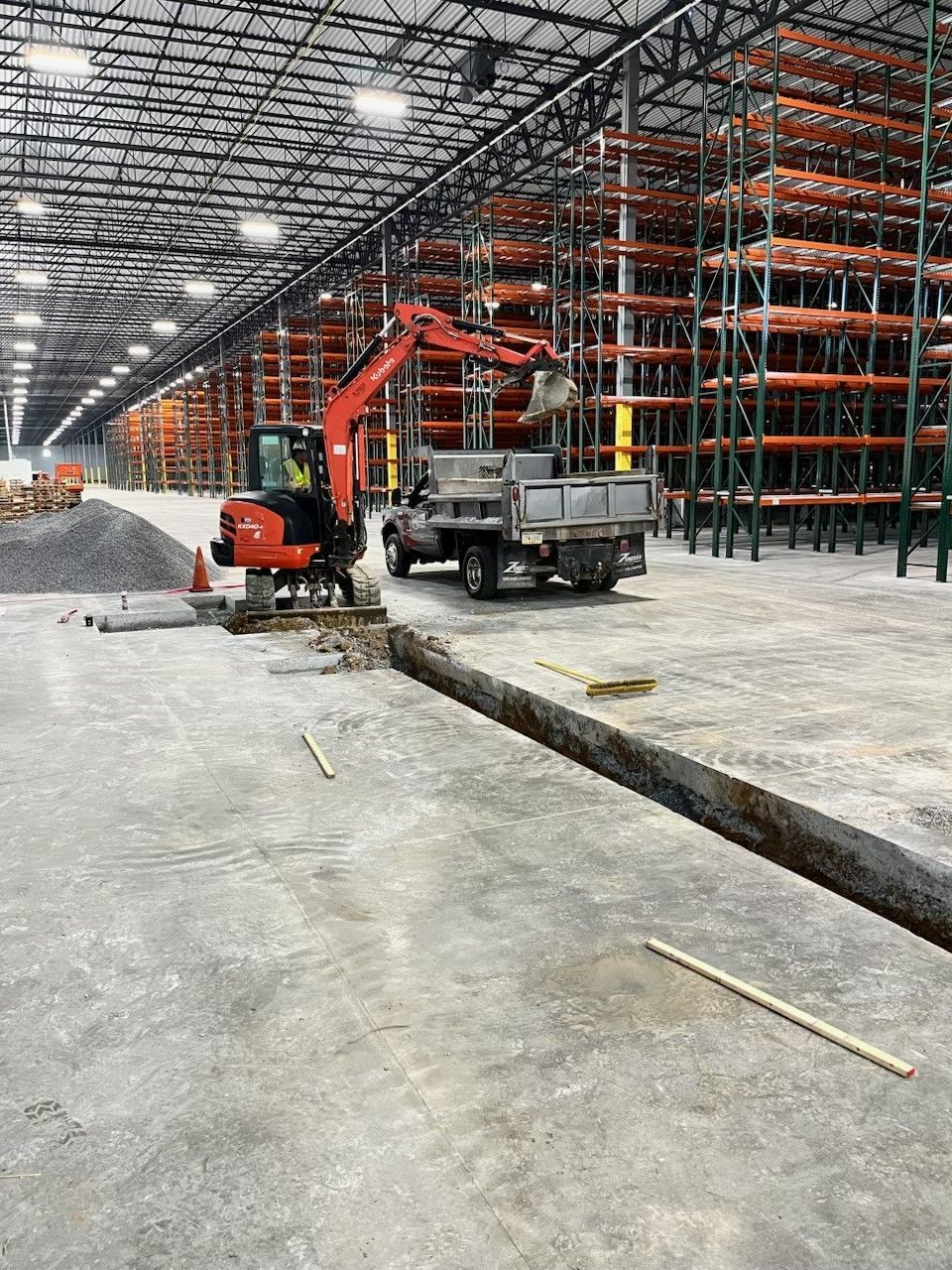 An excavator is digging a hole in a large warehouse.